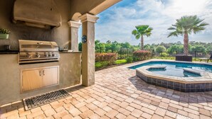 An outdoor kitchen with a grill and a hot tub. - Luxury Villa With Majestic Golf Course Views, Reunion Resort, Villa Orlando 1795 (Kissimmee)