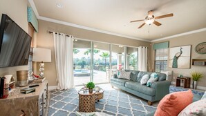 A spacious living room with a large sofa, a television, and a ceiling fan. - Luxury Villa With Majestic Golf Course Views, Reunion Resort, Villa Orlando 1795 (Kissimmee)