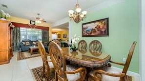 A dining area with a glass table, wooden chairs, and a chandelier.