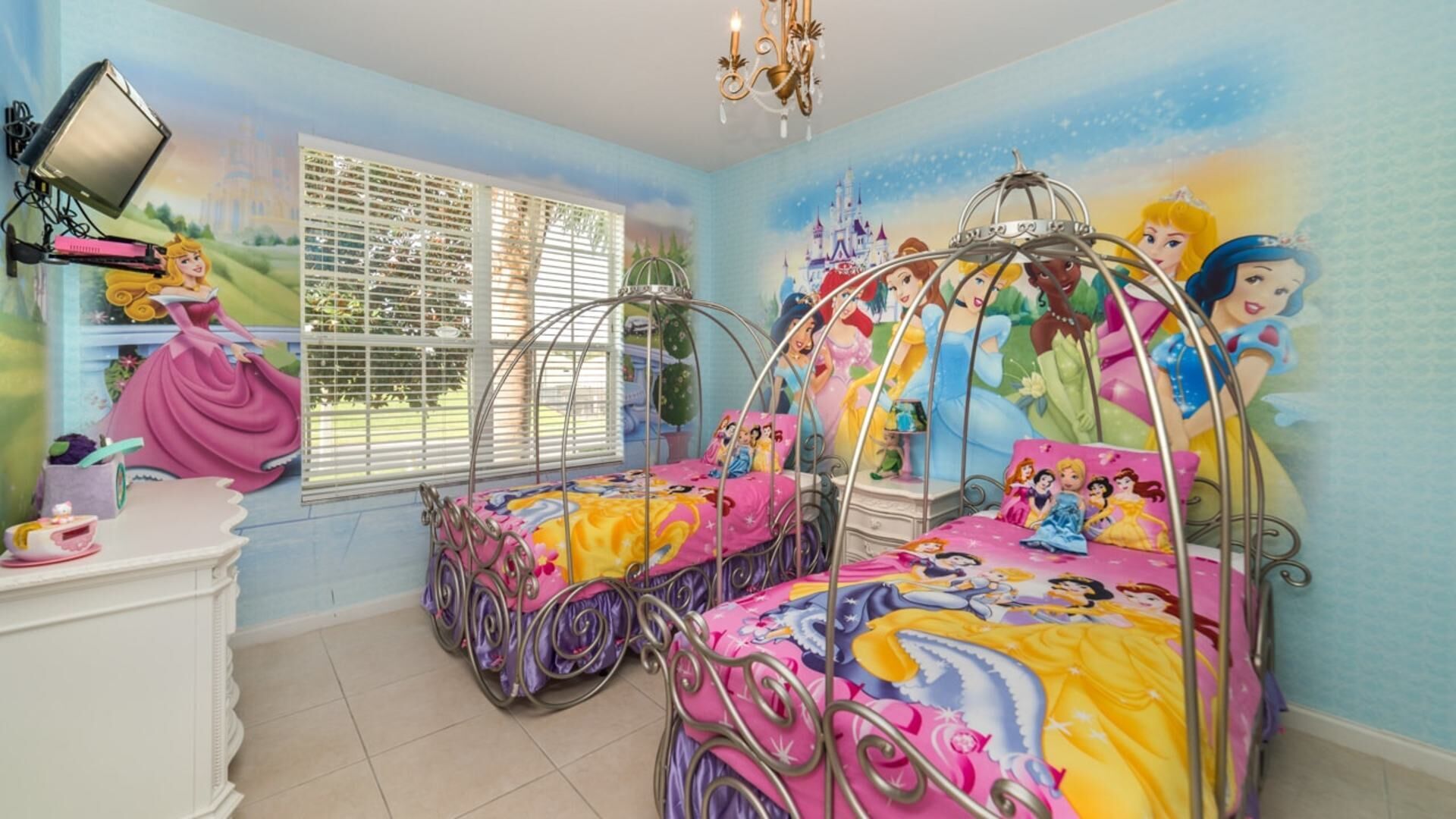 A children's bedroom with two beds, a dresser, and a mural of Disney princesses.