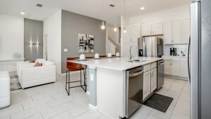 A modern kitchen with white cabinetry, stainless steel appliances, and pendant lighting. - Villa in Solterra Resort 2764 (Davenport)