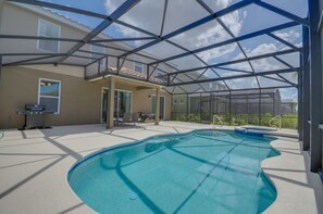 A covered outdoor swimming pool with a glass roof, surrounded by a patio area with chairs and a barbecue grill. - Villa in Solterra Resort 1510 (Davenport)