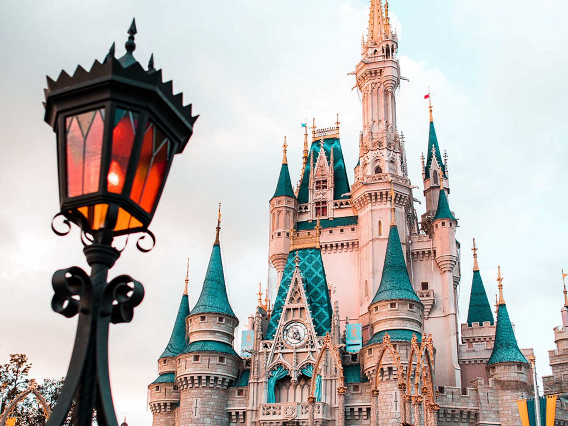 Une structure ressemblant à un château, dotée de nombreuses tours et flèches, un imposant clocher et un lampadaire au premier plan.