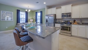 A modern kitchen with white cabinets, stainless steel appliances, and a granite countertop. - Villa in Solterra Resort 1510 (Davenport)