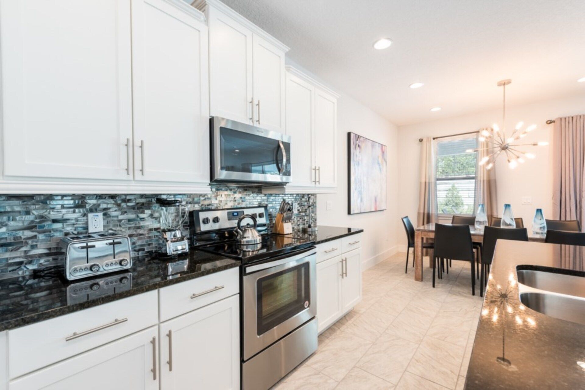 A modern kitchen with white cabinets, a stainless steel stove, and a black countertop.