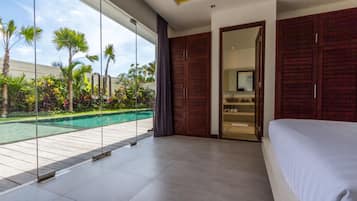 A modern hotel room with a large bed, a private bathroom, and a view of a swimming pool.