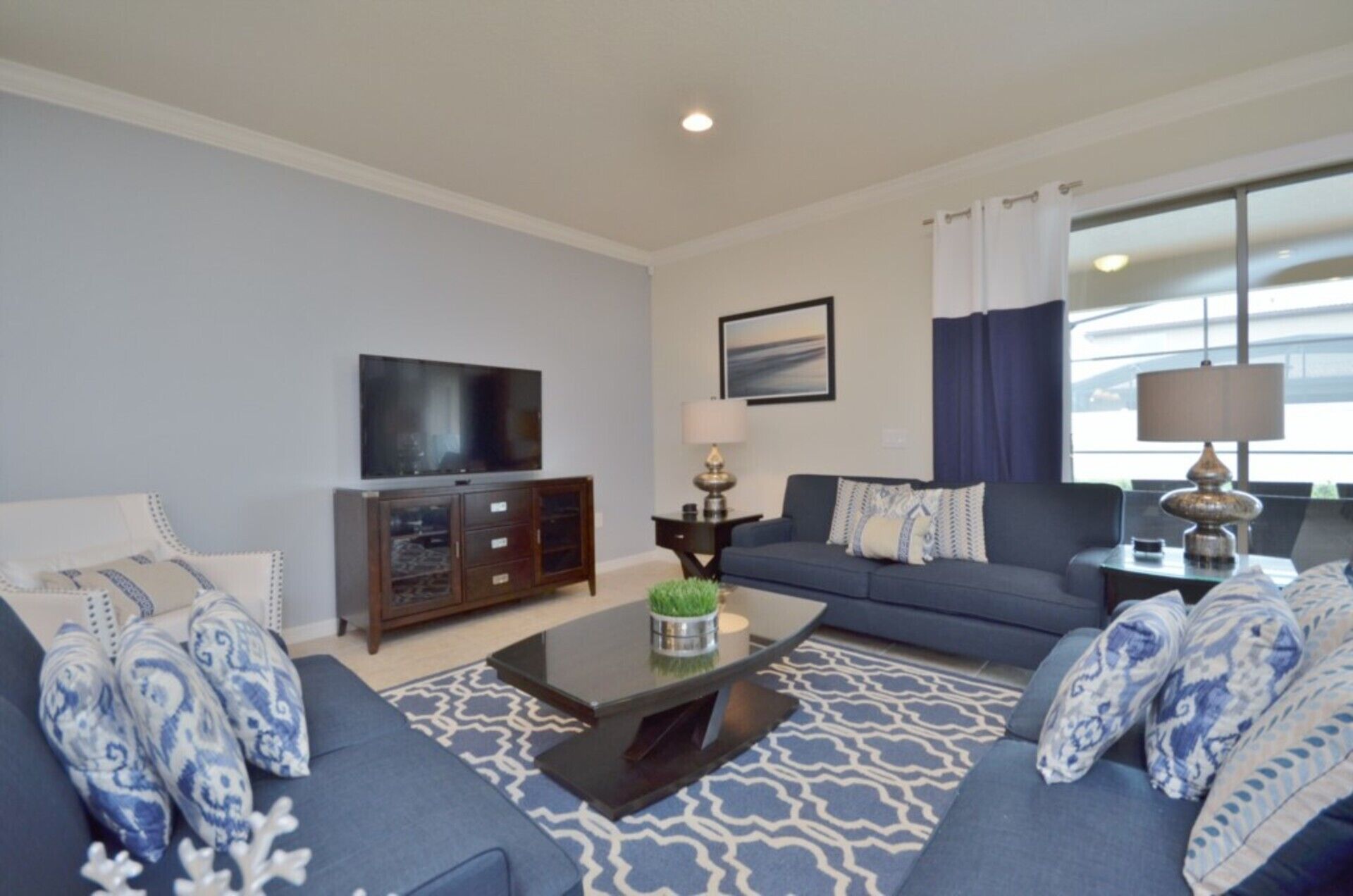 A living room with a sofa set, a coffee table, a TV, and a lamp.