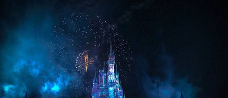 A castle-like structure with multiple spires and a central tower, illuminated by blue and white lights.