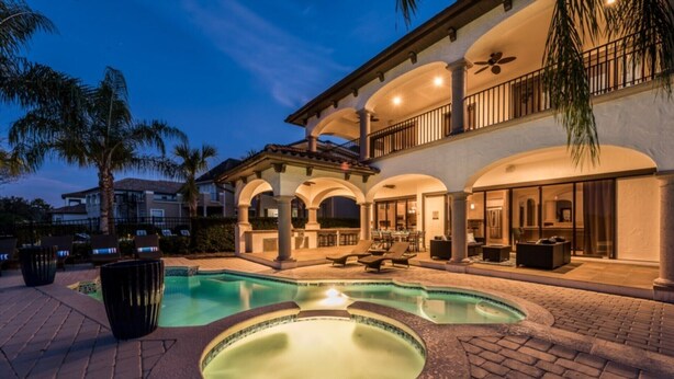 A luxurious outdoor pool area with a hot tub, lounge chairs, and a covered patio.