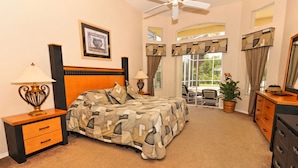 A bedroom with a bed, two bedside tables, a dresser, a ceiling fan, and a large window with curtains. - Perfect 5 Bed Villa for Rent on Highlands Reserve Resort, Villa Orlando 1450 (Davenport)