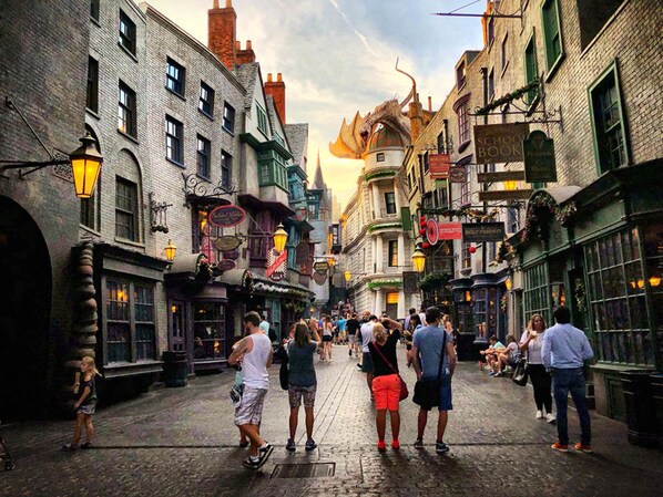 Une rue animée, bordée de bâtiments historiques, avec un pavé et une statue de dragon.