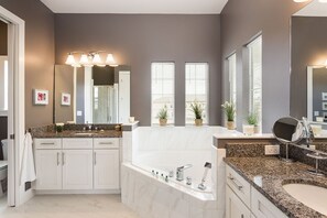 A modern bathroom with a large mirror, a bathtub, and a vanity with a sink. - Villa in Reunion Resort & Spa 1355 (Kissimmee)