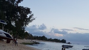 A beach with boats, people, and a lifeguard tower.