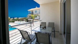 A balcony with a table and chairs, overlooking a swimming pool and buildings. - Beautiful Apartment With Communal Pool, Protaras Apartment 1287 (Paralimni)