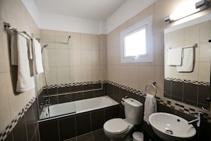 A bathroom with a bathtub, toilet, and sink, featuring checkered tiles and a window. - Beautiful Apartment With Communal Pool, Protaras Apartment 1287 (Paralimni)
