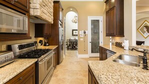 A kitchen with granite countertops, stainless steel appliances, and wooden cabinets. - Villa in Reunion Resort & Spa 1336 (Kissimmee)