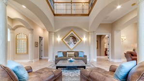 A spacious living room with a high ceiling, a central seating area with a sofa and two armchairs, and a large decorative mirror on the wall. - Villa in Reunion Resort & Spa 1336 (Kissimmee)