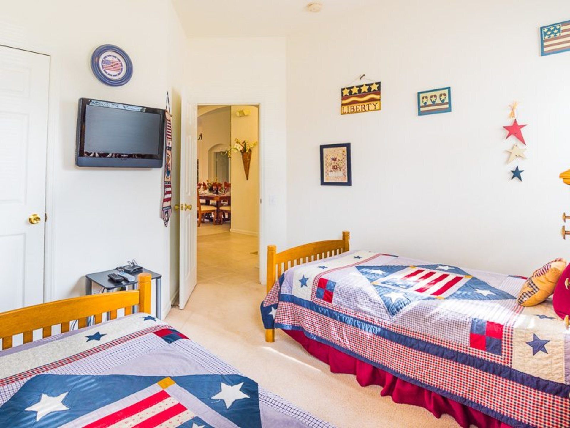 A bedroom with two beds, a television, and patriotic decorations.