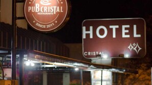 Entrada de un hotel con un letrero que dice 'CRISTAL' y un letrero de 'PUB CRISTAL RESTAURANTE'.