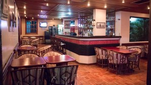 Un restaurante con piso de madera, una zona de bar y varias mesas y sillas.