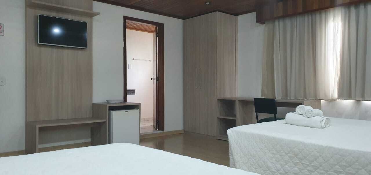 A hotel room with a bed, a desk, a TV, and a door leading to a bathroom.