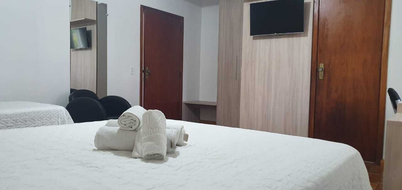 A hotel room with a bed, a wardrobe, a television, and a desk with a chair.