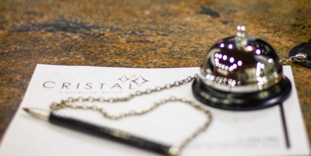 Un escritorio con una pluma, un papel con el texto "CRISTAL" y un objeto decorativo.