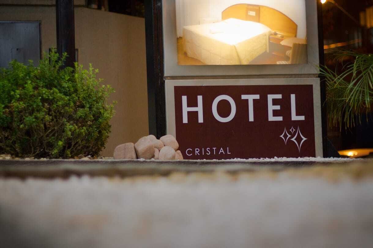 Placa de hotel com o nome 'HOTEL CRISTAL' e uma imagem de uma cama.