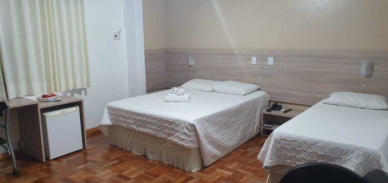 A hotel room with two beds, a small desk, and a chair.
