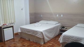 A hotel room with two beds, a small desk, and a chair.