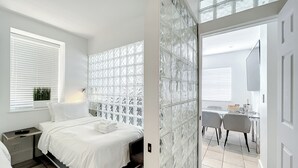 Ein modernes Schlafzimmer mit Bett, Nachttisch und einem Fenster mit Jalousien.