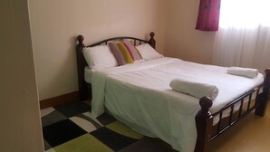 A neatly made bed with white bedding, a colorful striped pillow, and a white towel on the side. - By Grace apartment near sportman arms,hosted by regina (Nanyuki)