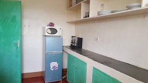 A compact kitchenette with a microwave, a small refrigerator, and a coffee machine. - By Grace apartment near sportman arms,hosted by regina (Nanyuki)