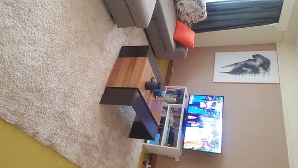 A living room with a sofa, a coffee table, a TV, and a rug. - By Grace apartment near sportman arms,hosted by regina (Nanyuki)