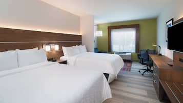 A hotel room with two beds, a desk, a chair, a television, and a window with a view.