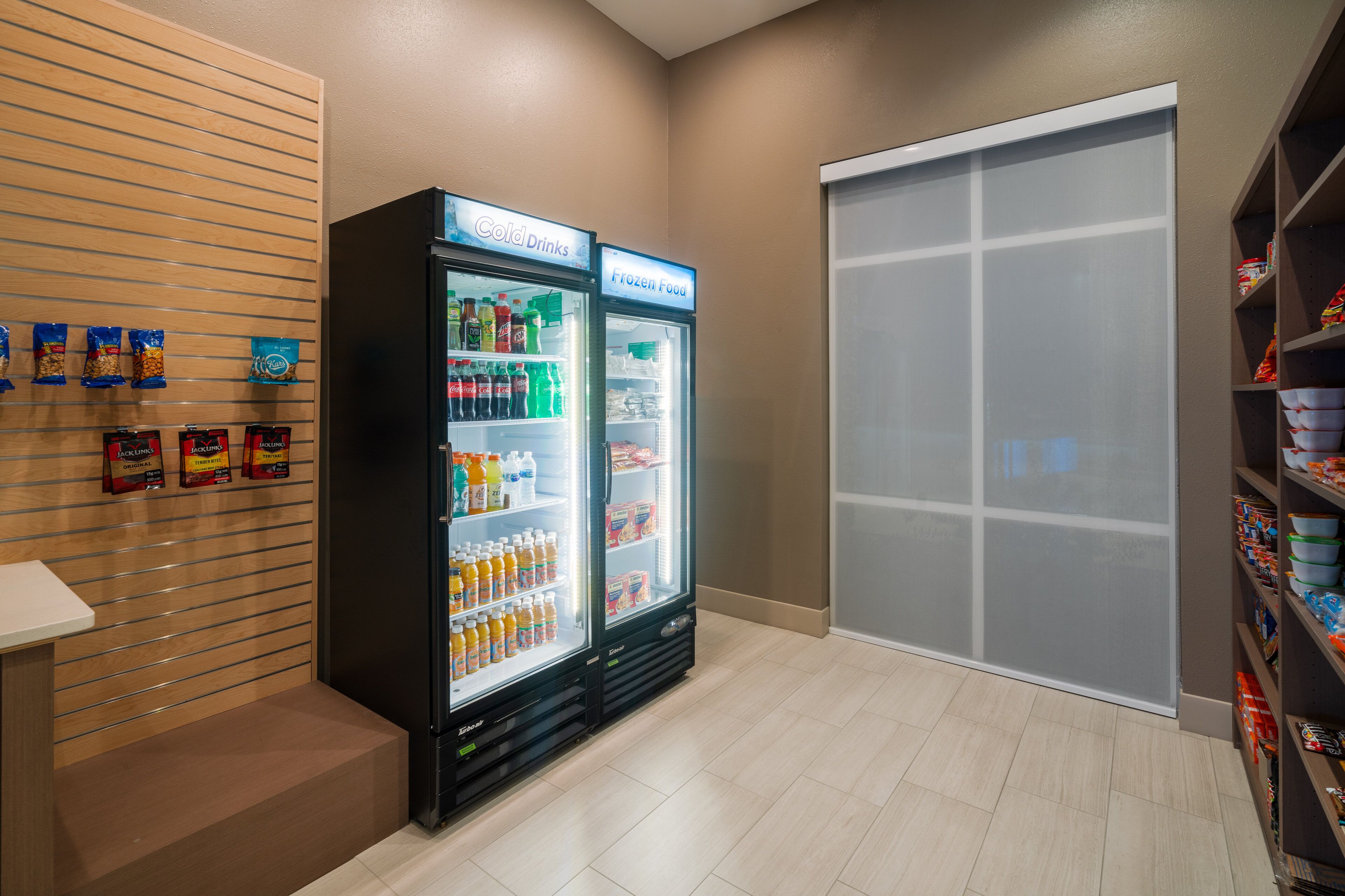 A vending area with two beverage dispensers labeled "Coli Drinks" and "Frozen Food," and snack packages on the wall.