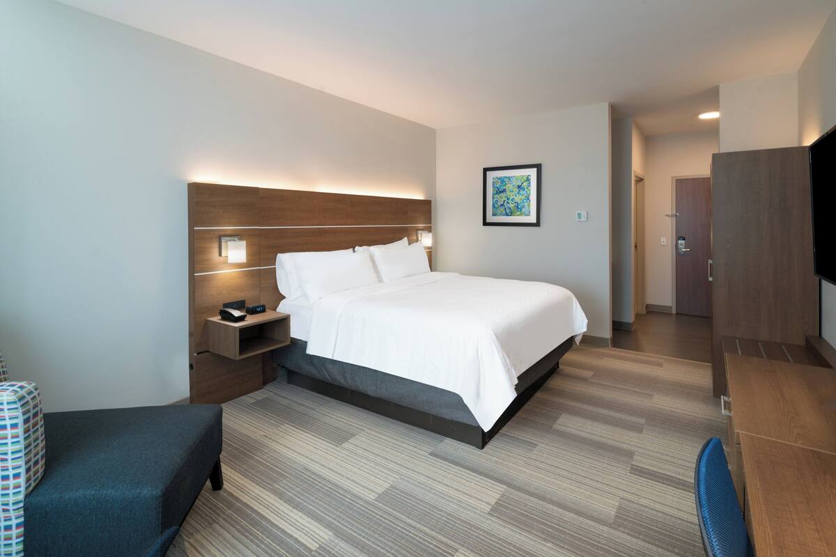A modern hotel room with a large bed, bedside tables, a desk, and a TV.