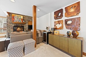 Ein modernes Wohnzimmer mit Kamin aus Stein, einer Couch, einem Couchtisch und einer Wanddekorierung mit Holzarbeiten.