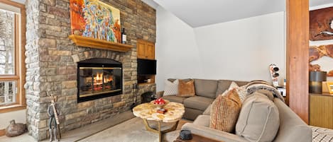 A living room with a stone fireplace, a large sofa, and a coffee table.