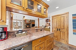 A kitchen with wooden cabinets, a granite countertop, a dishwasher, and a fireplace.