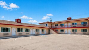 A motel with multiple rooms, a parking lot, and a staircase leading to a balcony.
