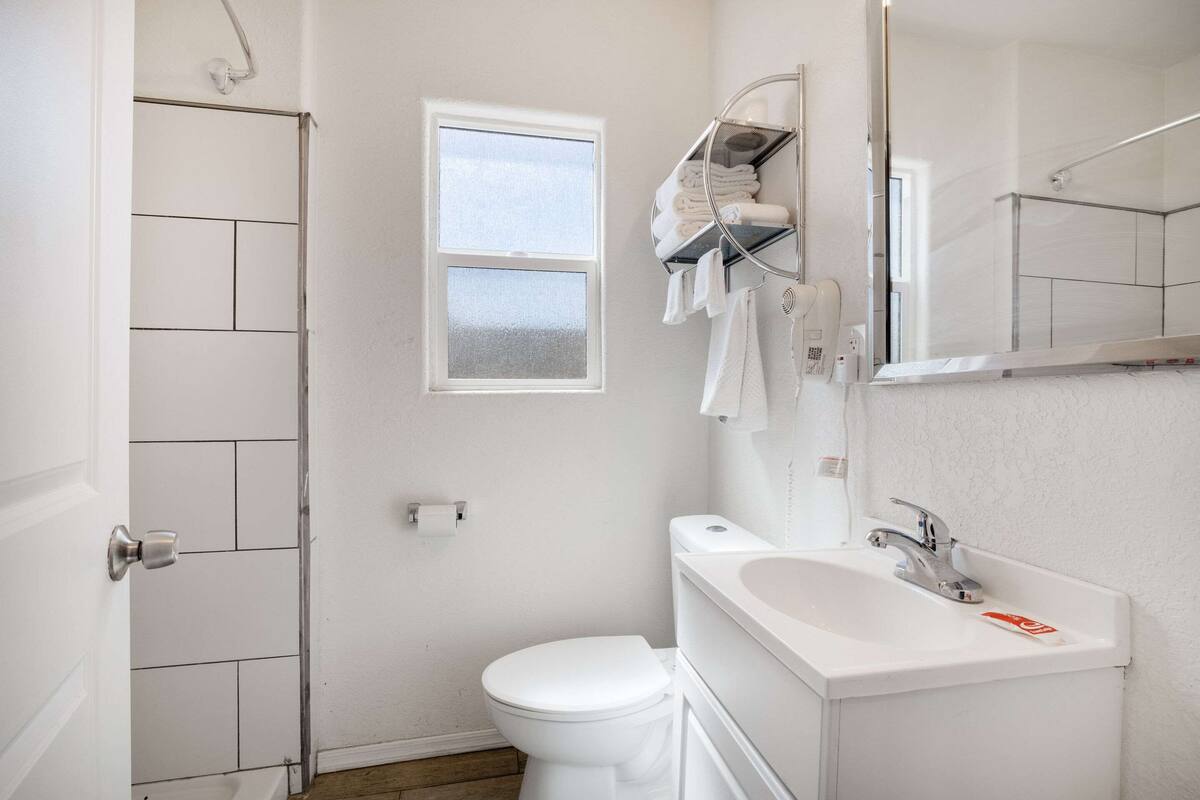 A bathroom with a white toilet, a sink, a mirror, and a towel rack.