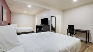 A hotel room with a large bed, a desk, a chair, and a television.
