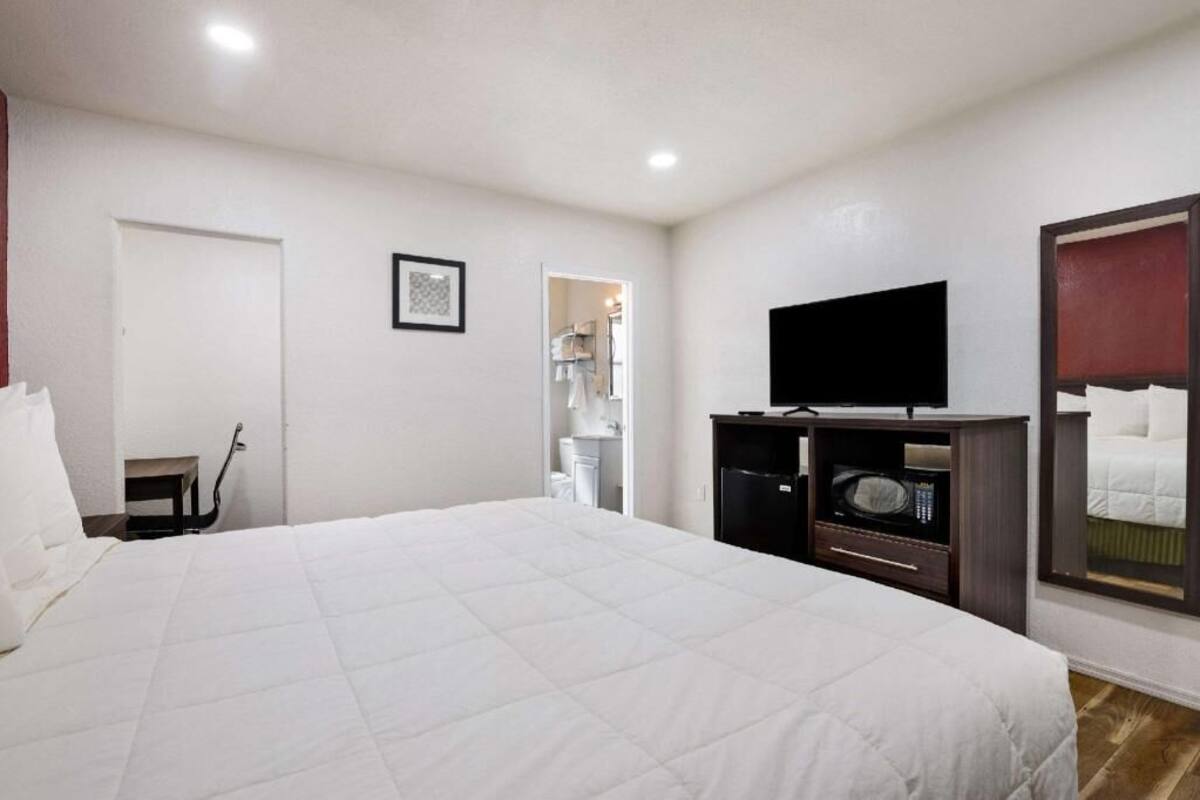 A hotel room with a large bed, a television, a microwave, and a door leading to a bathroom.