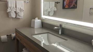 A modern bathroom with a large mirror, a sink, and a towel rack.