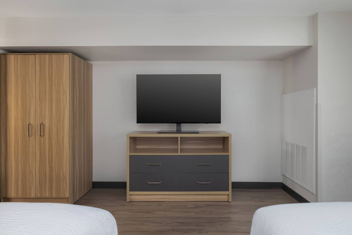Een slaapkamer met een bed, een kledingkast, een tv-meubel en een verwarming.