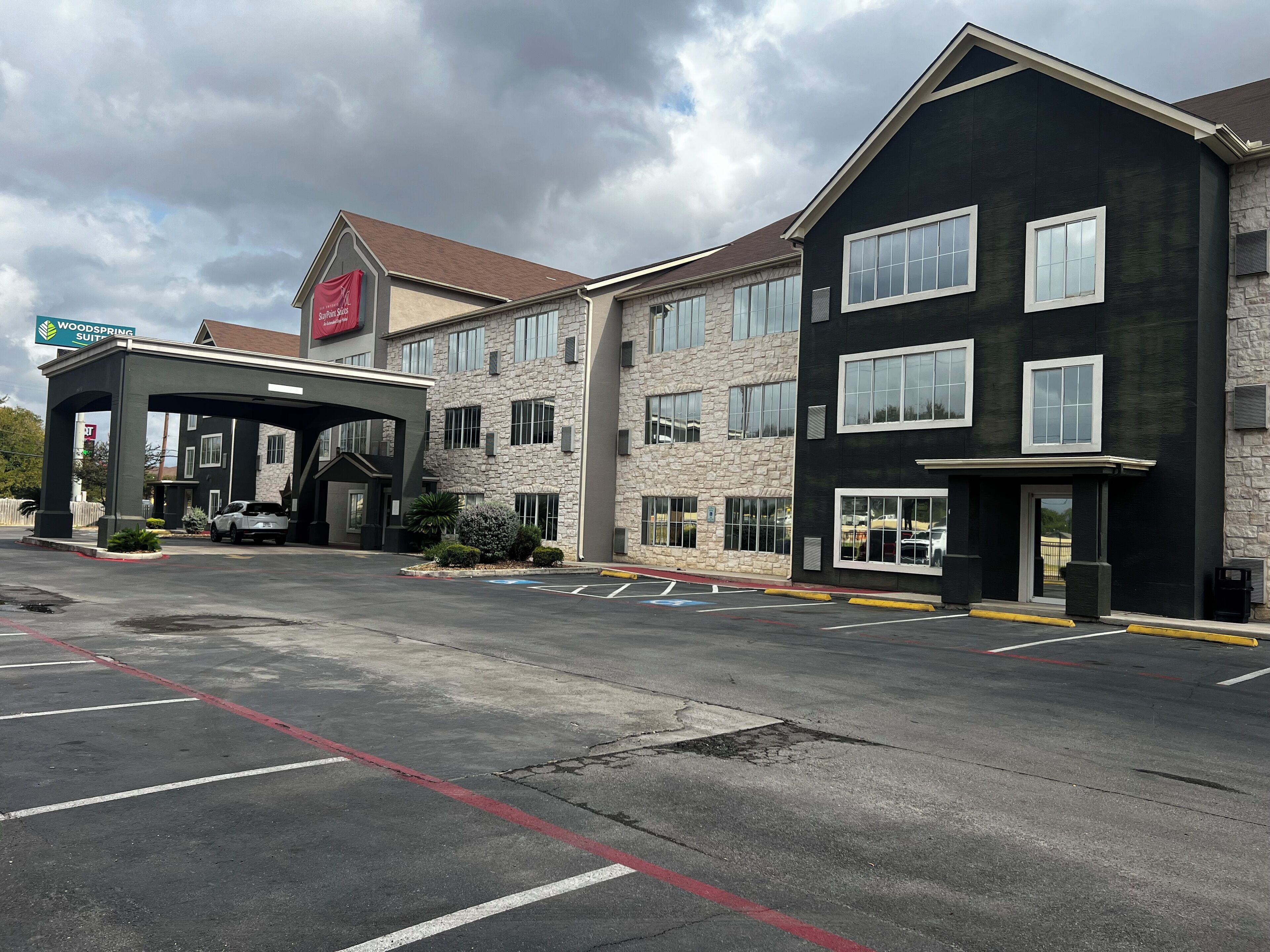 A hotel with a stone facade, multiple windows, and a covered entrance.