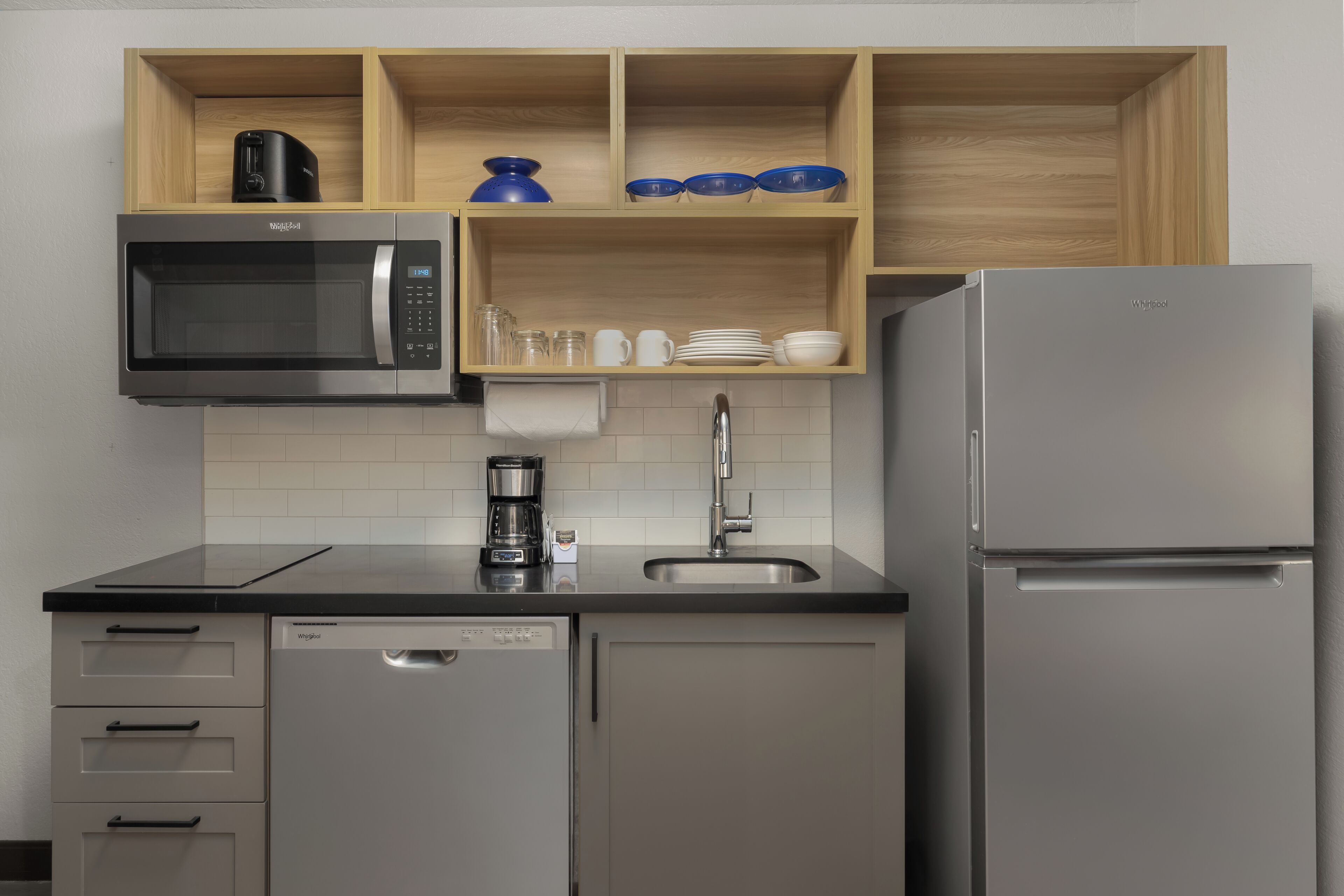 Una cocina equipada con microondas, cafetera, lavaplatos y refrigerador.
