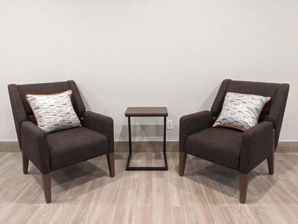 Two armchairs with patterned cushions and a small table between them.
