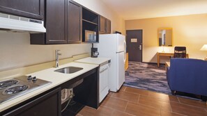 Cozy retreat with a kitchenette, featuring a stove, sink, and refrigerator, plus a comfortable seating area with a table and chair.